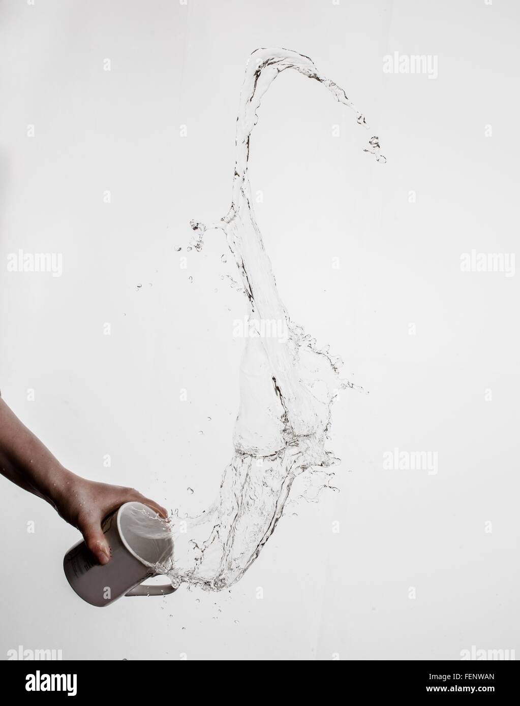 Person throwing mug of water, white background Stock Photo