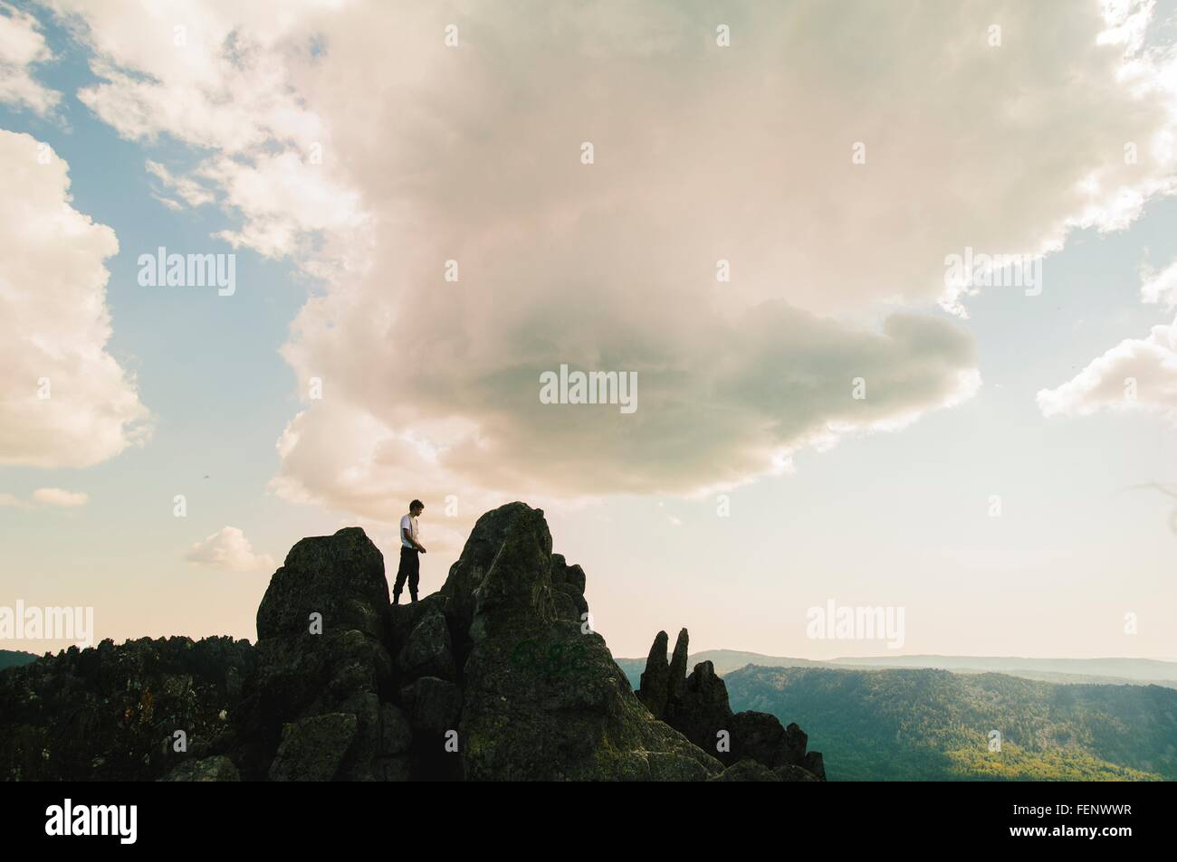 Silhouetted teenage male hiker on top of rugged rock formation, Russia Stock Photo