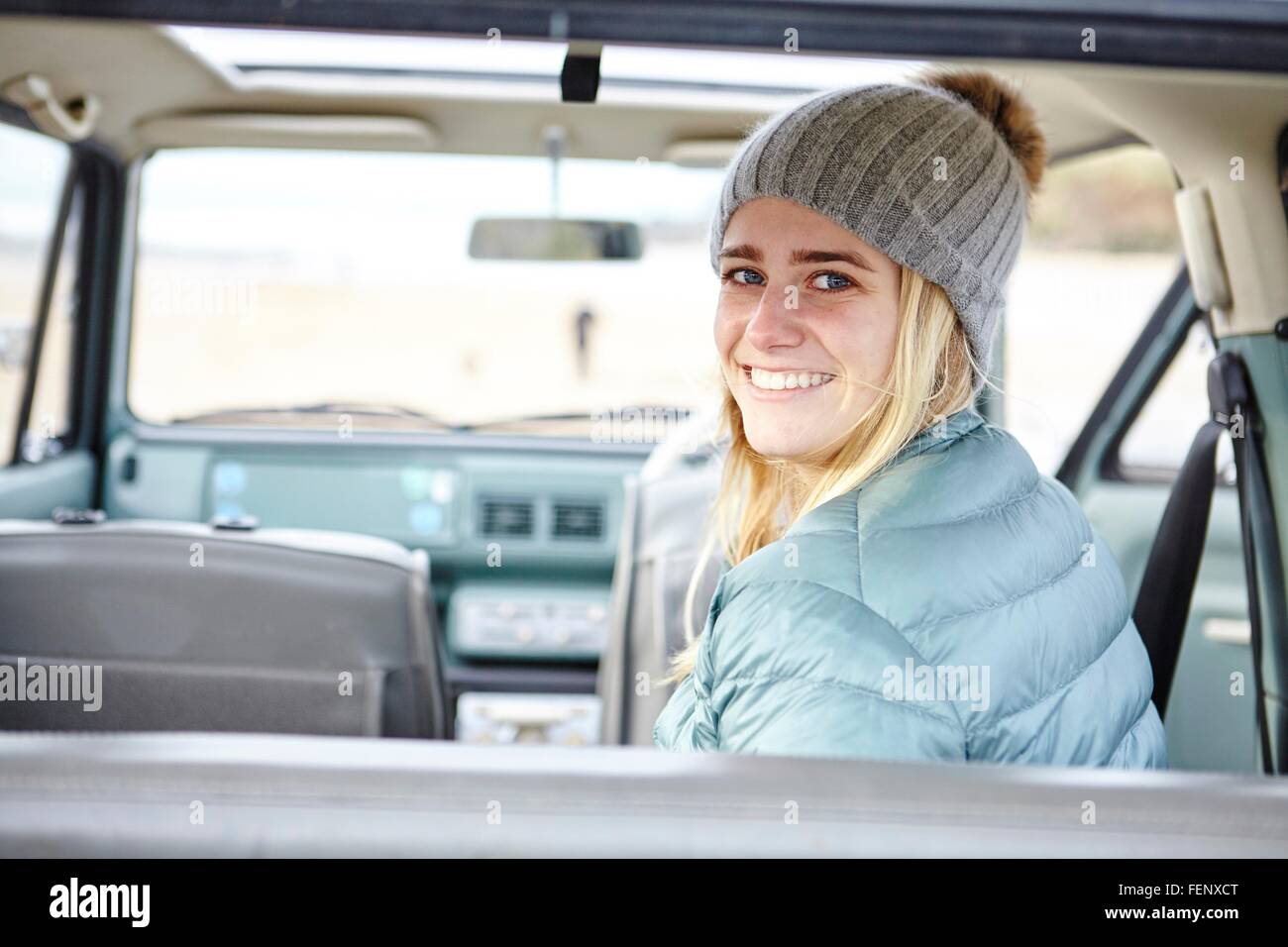 Portrait of young woman in car at beach wearing knit hat Stock Photo