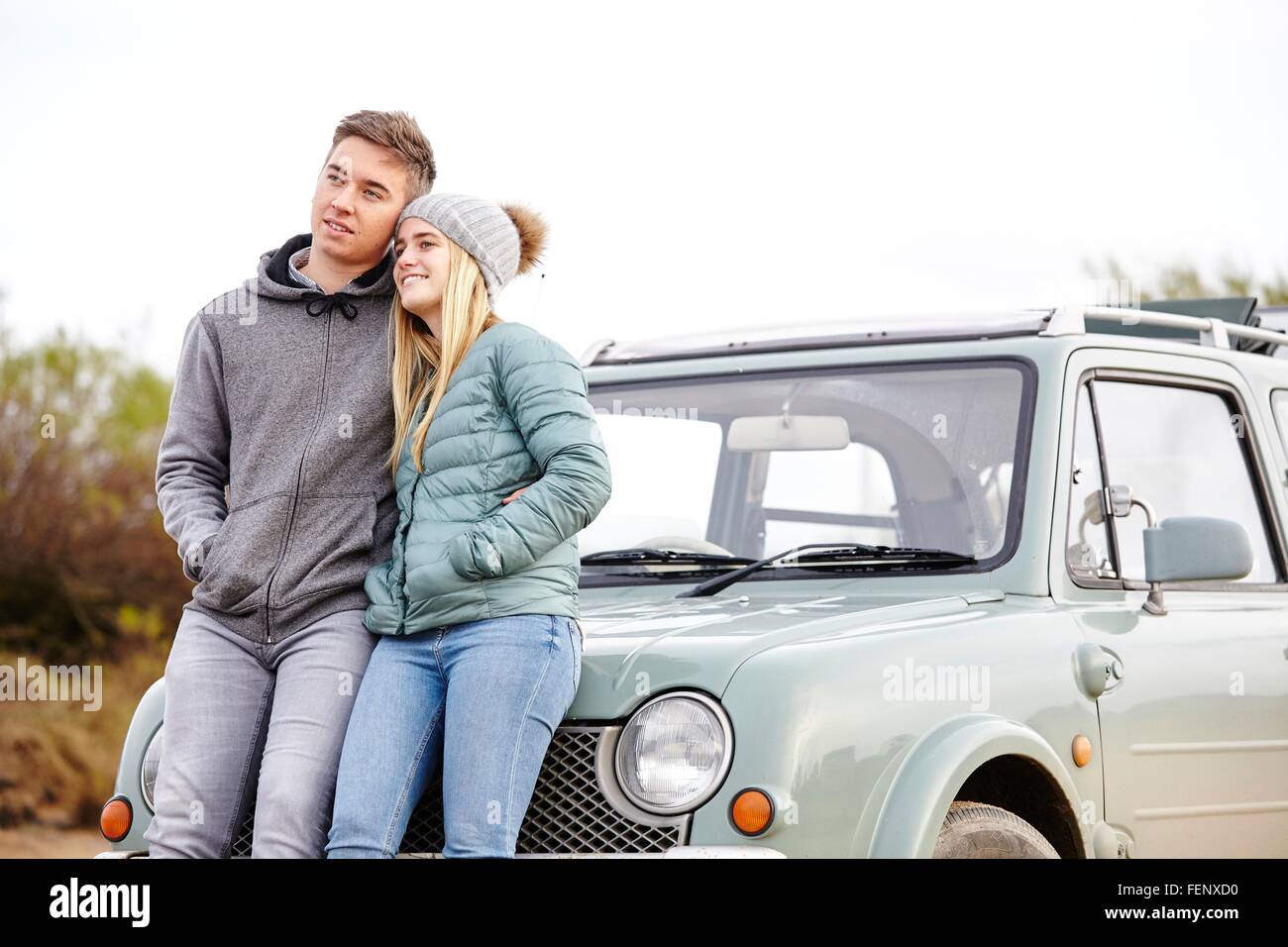 Romantic young couple leaning against car at beach Stock Photo
