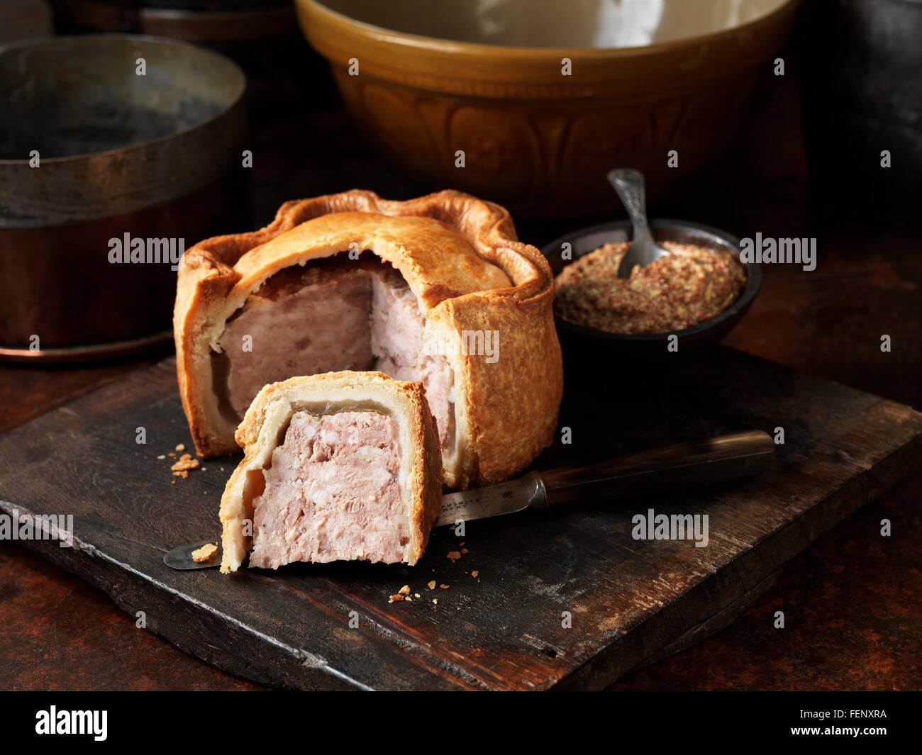 Sliced Melton Mowbray pork pie with wholegrain mustard on wooden cutting board Stock Photo