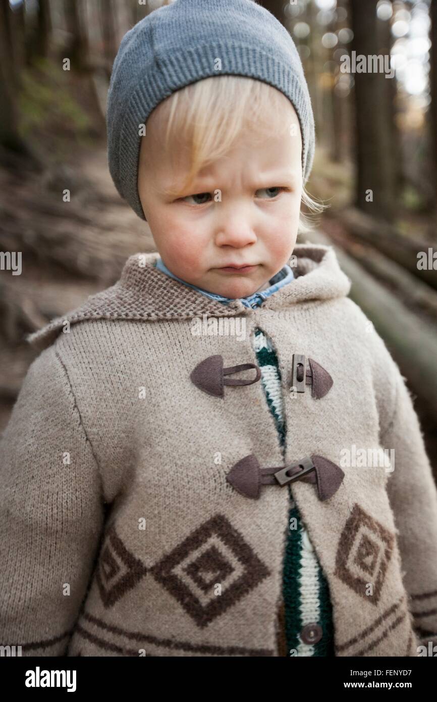 Portrait of frowning female toddler wearing knit hat in forest Stock Photo