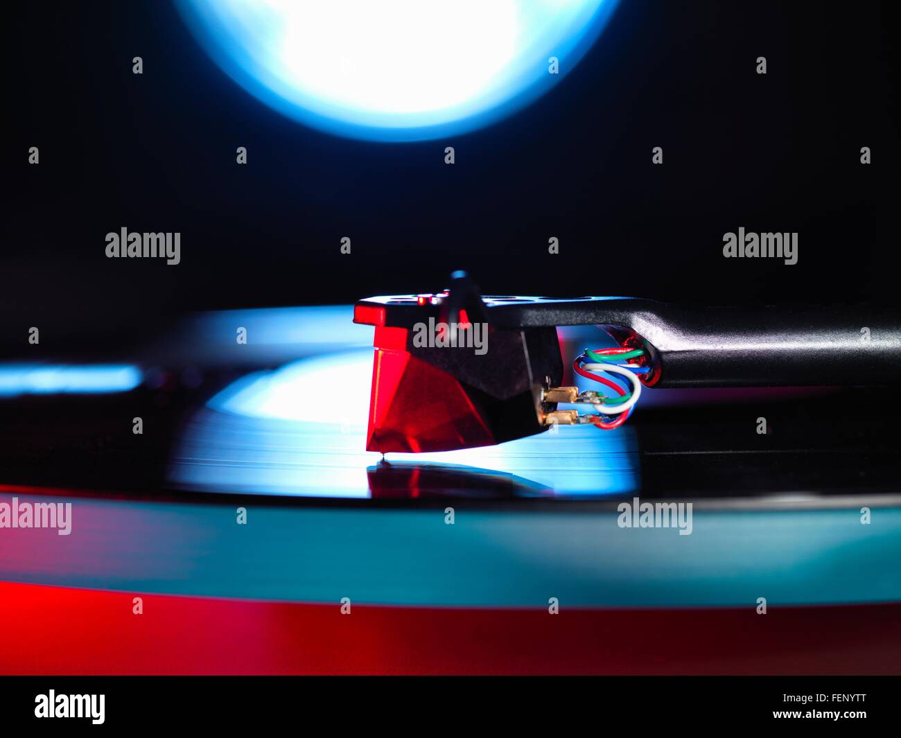 Close up of spot lit turntable and red stylus playing a vinyl record Stock Photo