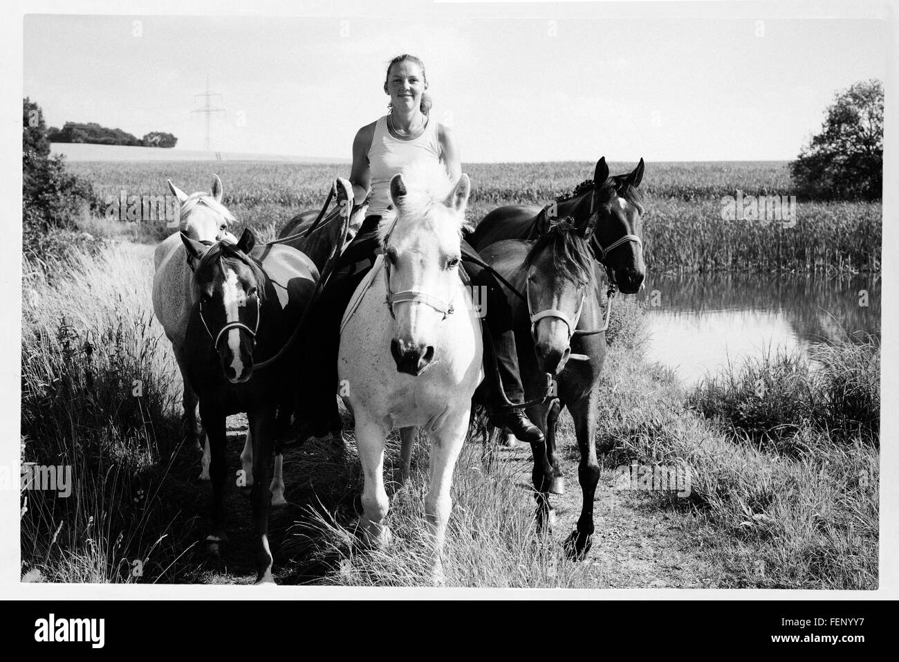 B&W image of woman riding and leading six horses on dirt track Stock ...