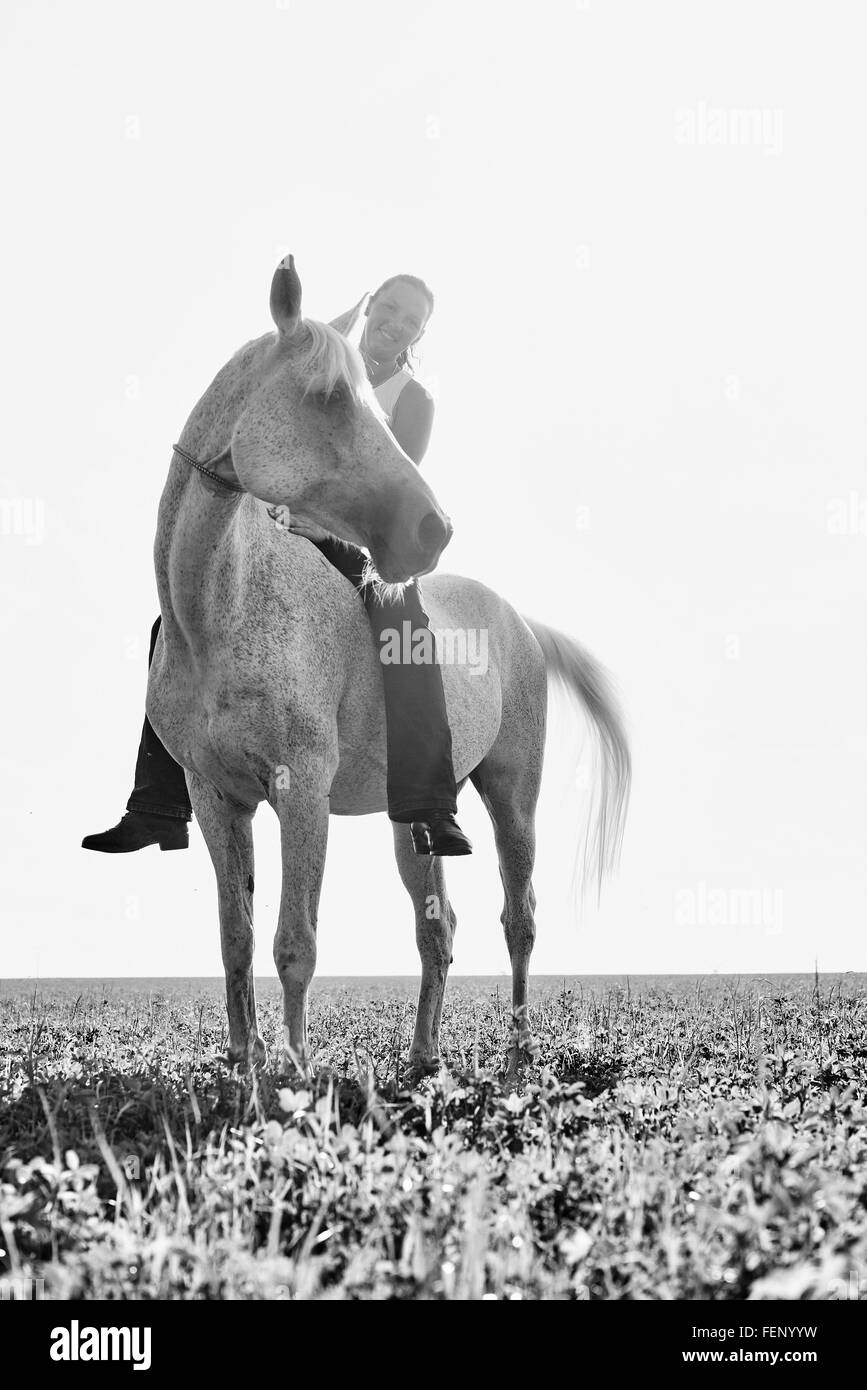 B&W portrait of woman riding horse bareback in field Stock Photo