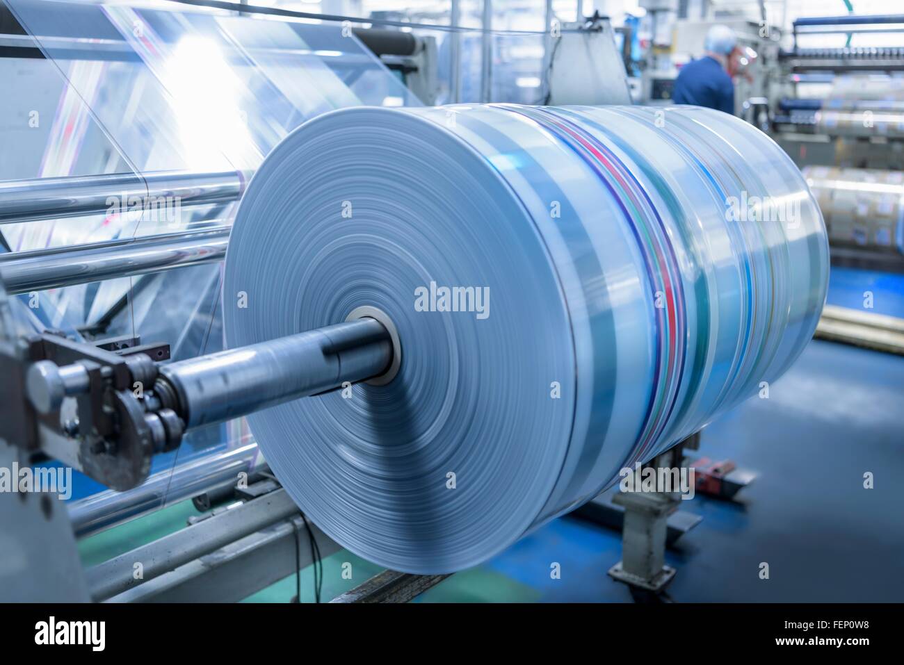 Spinning roll of printed packaging in food packaging printing factory Stock Photo
