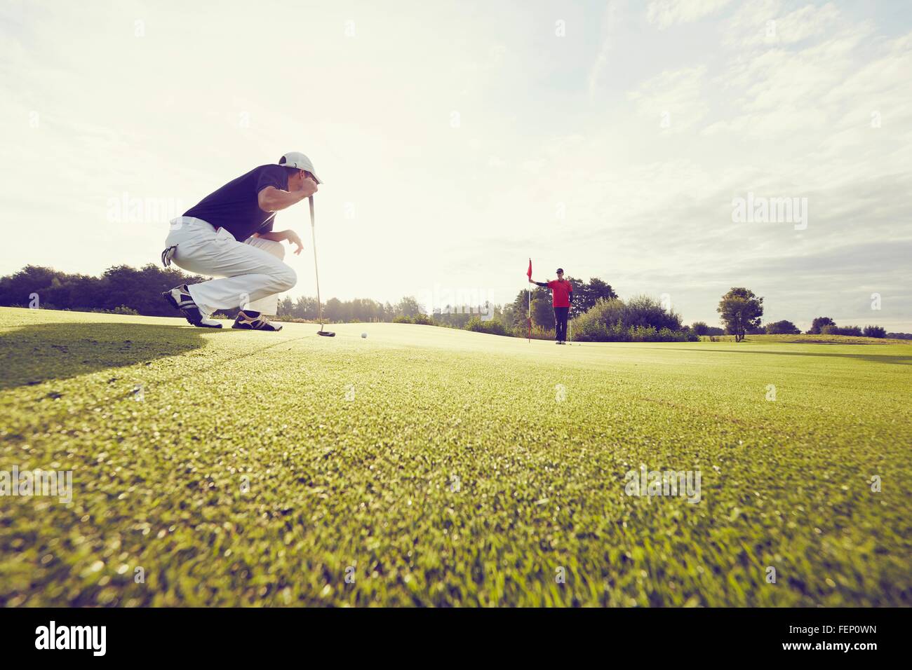 Golfer crouching on course, Korschenbroich, Dusseldorf, Germany Stock Photo