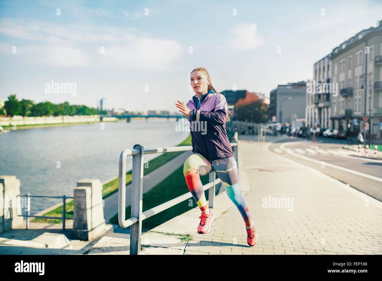 Mid adult female runner running along riverside Stock Photo