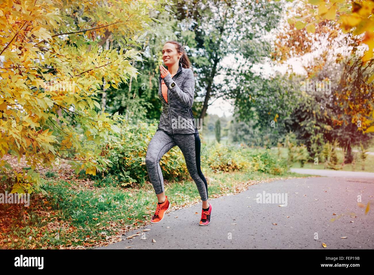 Mid adult female runner running along park path Stock Photo