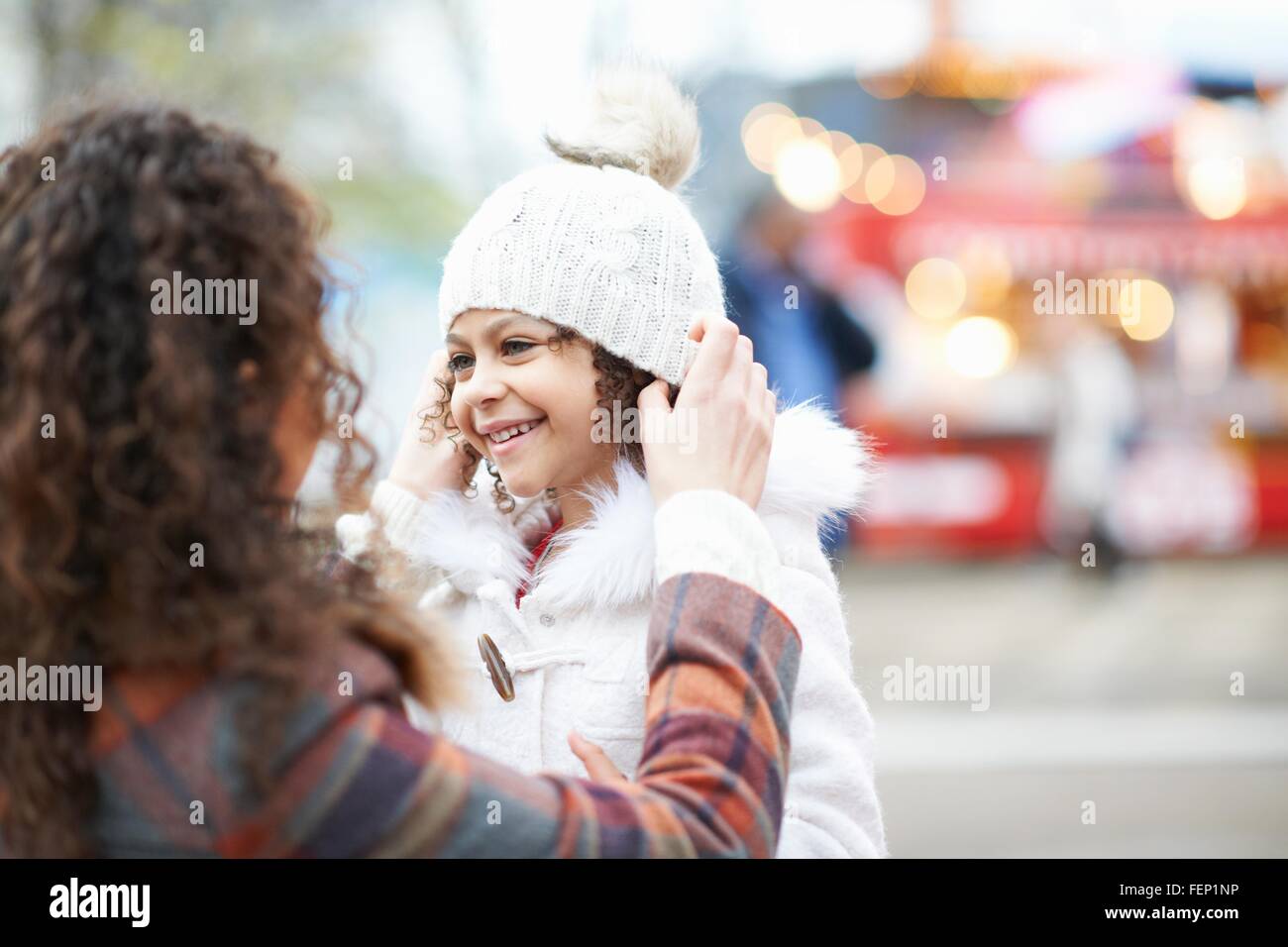 Mother putting knit hat on smiling daughter Stock Photo