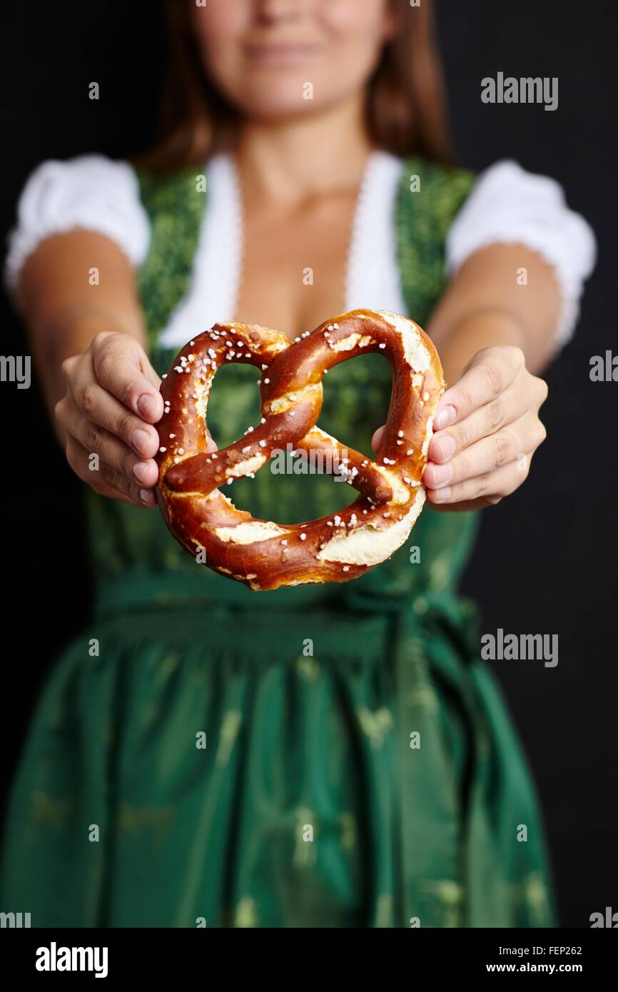 Young woman in Dirndl holding pretzel Stock Photo