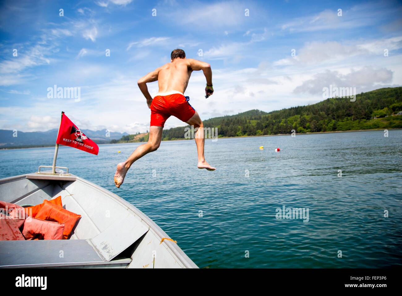 Mid adult man jumping into sea from boat, Nehalem Bay, Oregon, USA Stock Photo