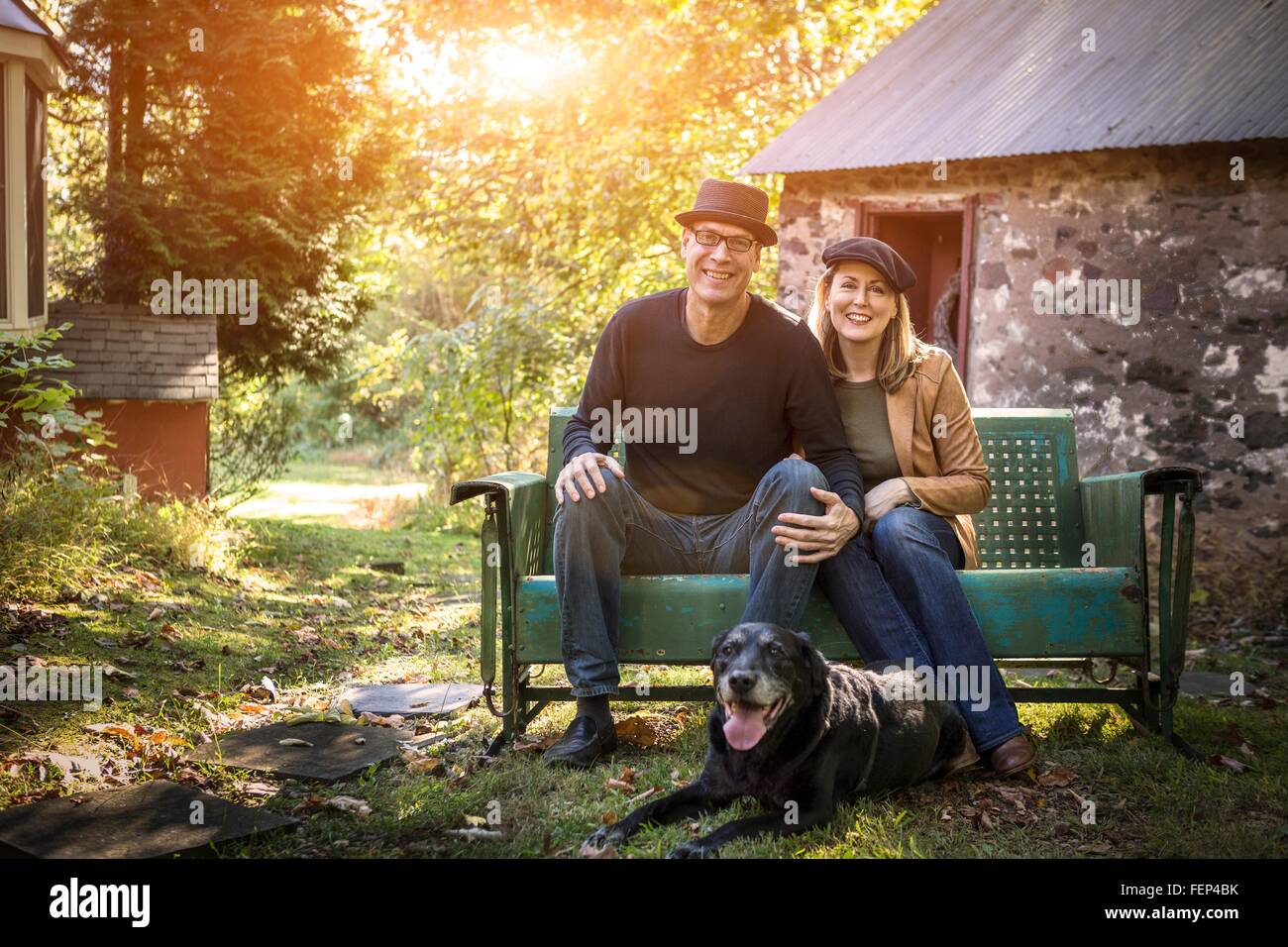 Portrait of mature couple with dog, sitting on bench, outdoors Stock ...