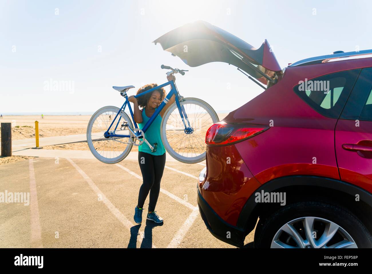 Mid adult woman putting bicycle into car boot Stock Photo