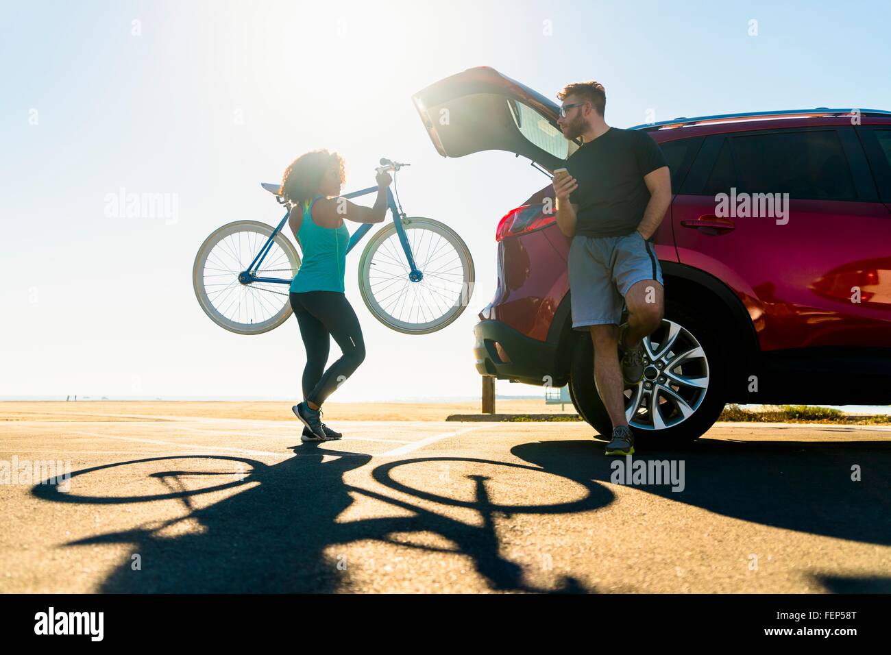 Mid adult woman putting bicycle into car boot Stock Photo