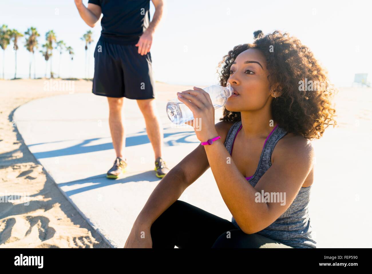 Mid adult woman, by beach, drinking from water bottle Stock Photo