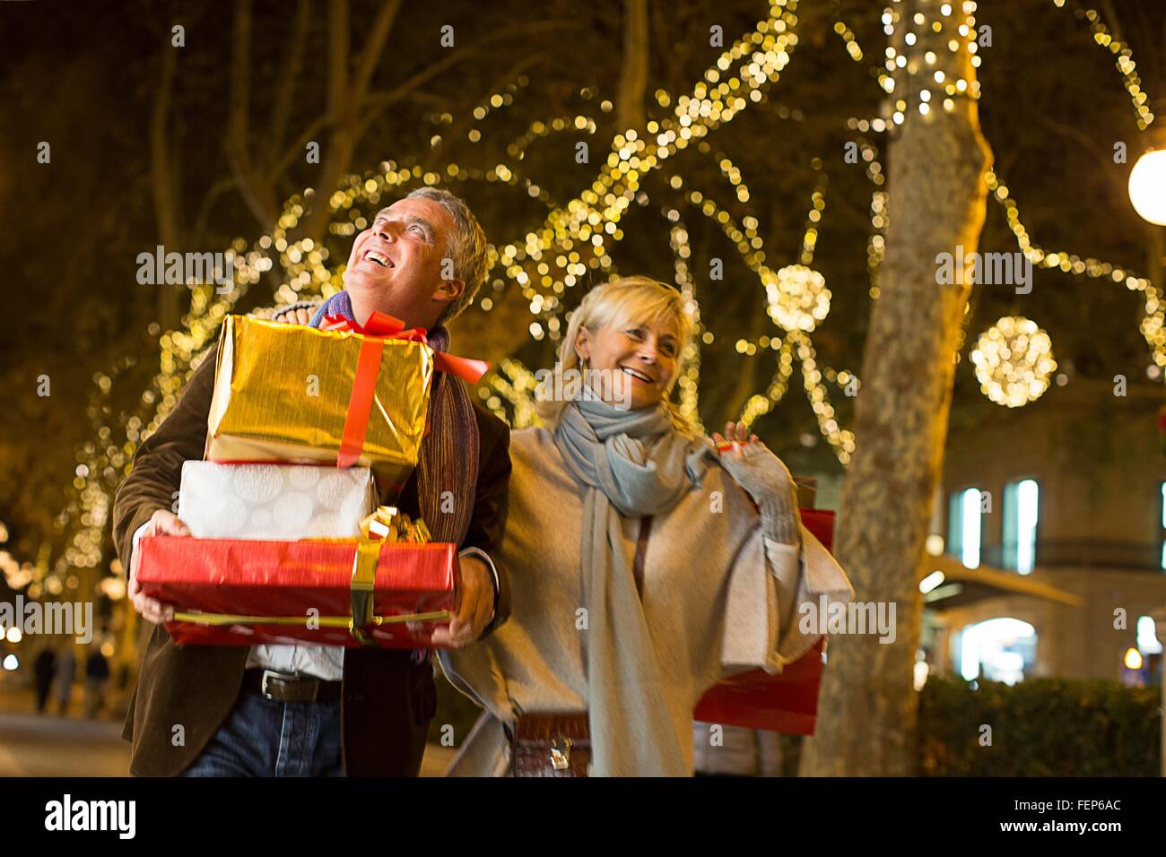 Mature couple strolling with xmas shopping on tree lined avenue, Majorca, Spain Stock Photo