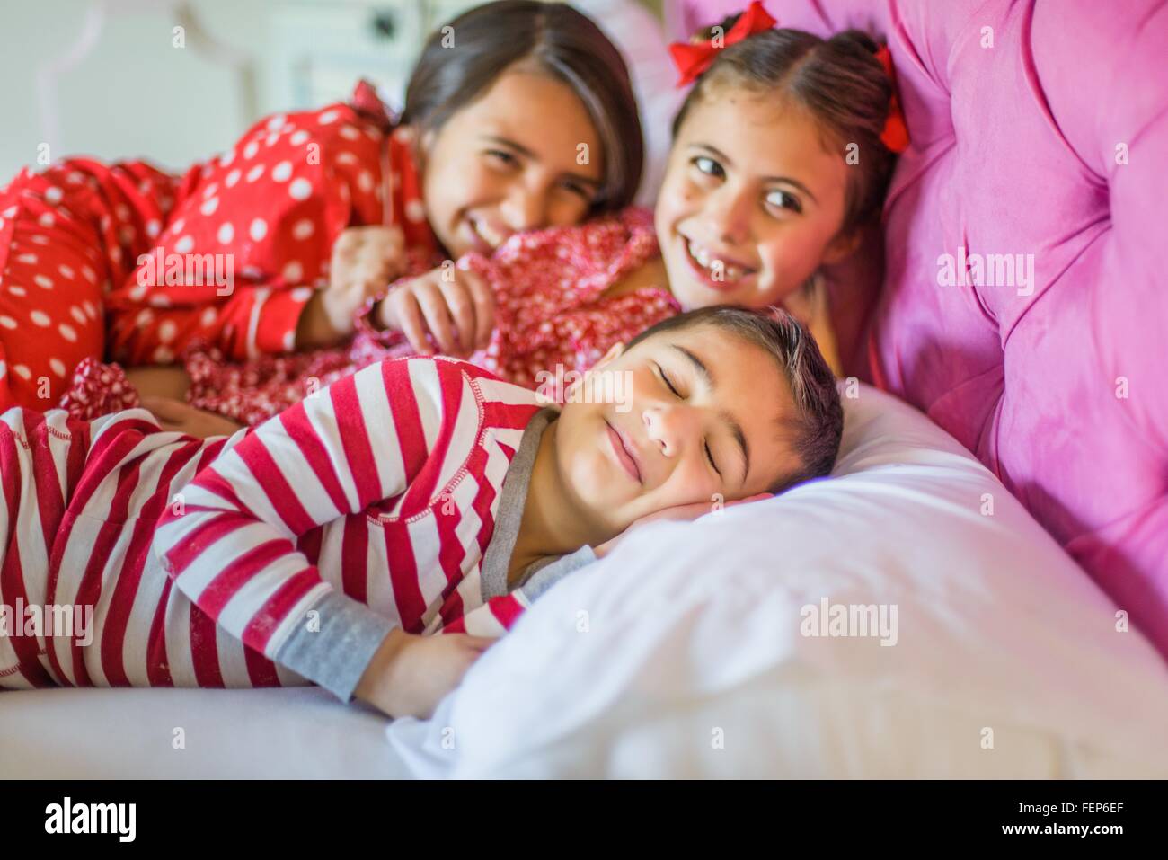 Cute boy and two sisters lying in bed giggling Stock Photo
