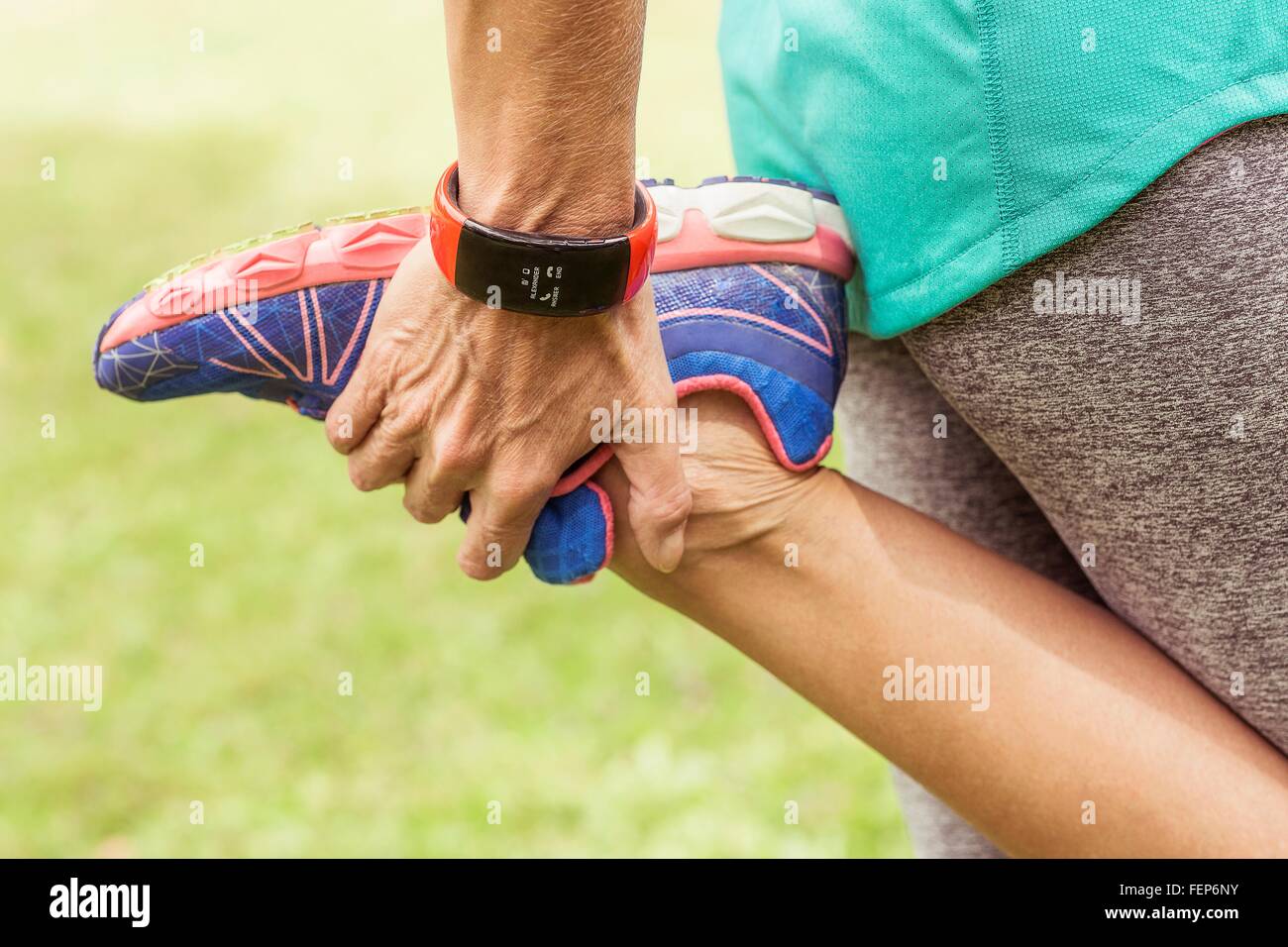 Mature woman, holding foot, stretching, mid section Stock Photo