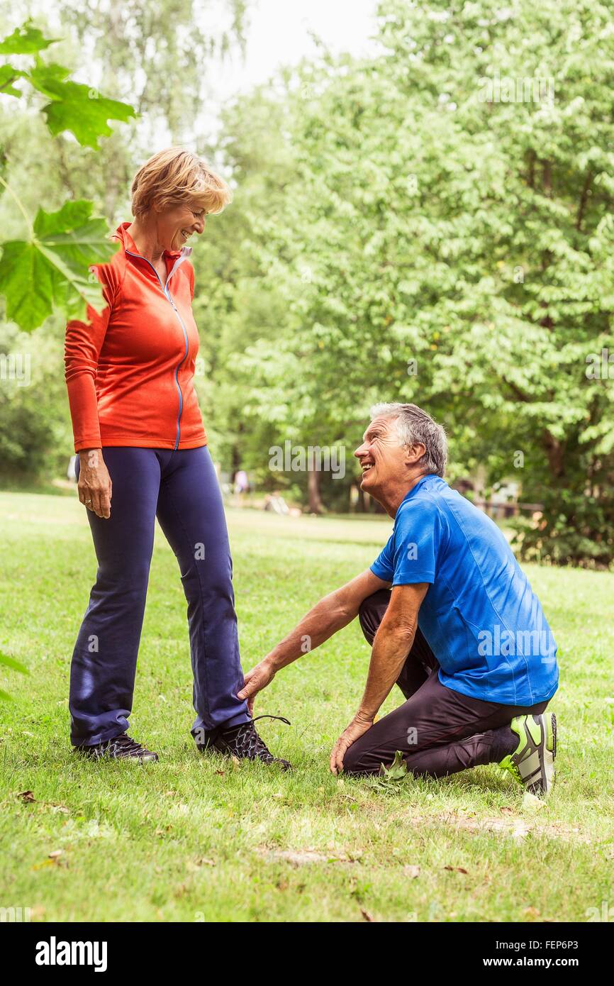 Couple exercising outdoors, senior man holding mature woman's ankle Stock Photo
