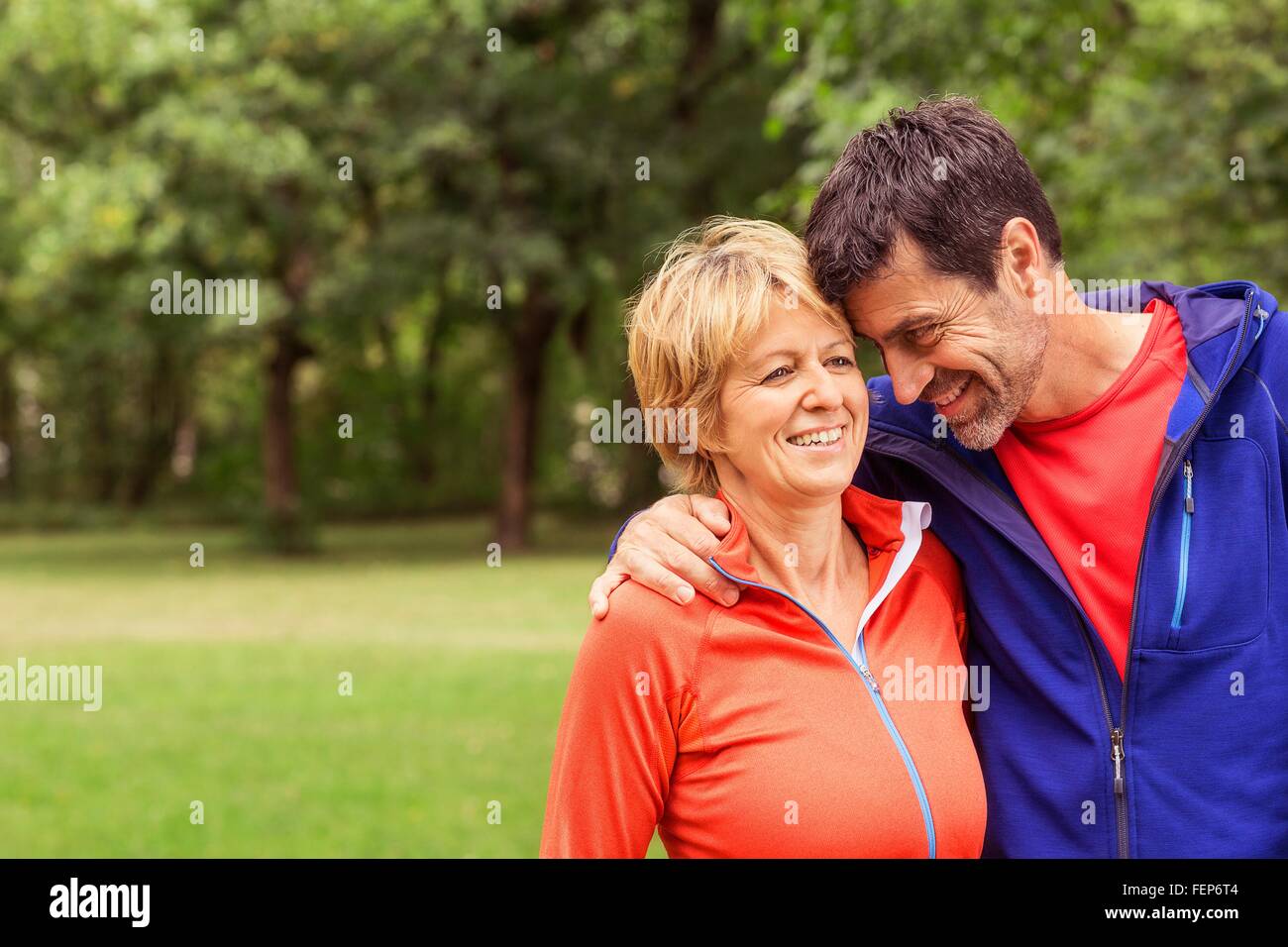 Couple wearing sports clothing, outdoors, hugging, smiling Stock Photo