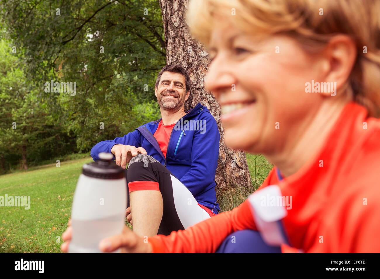 Couple relaxing, following exercise, holding water bottle Stock Photo
