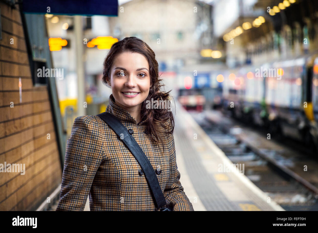 Young woman in brown winter coat waiting on train station Stock Photo