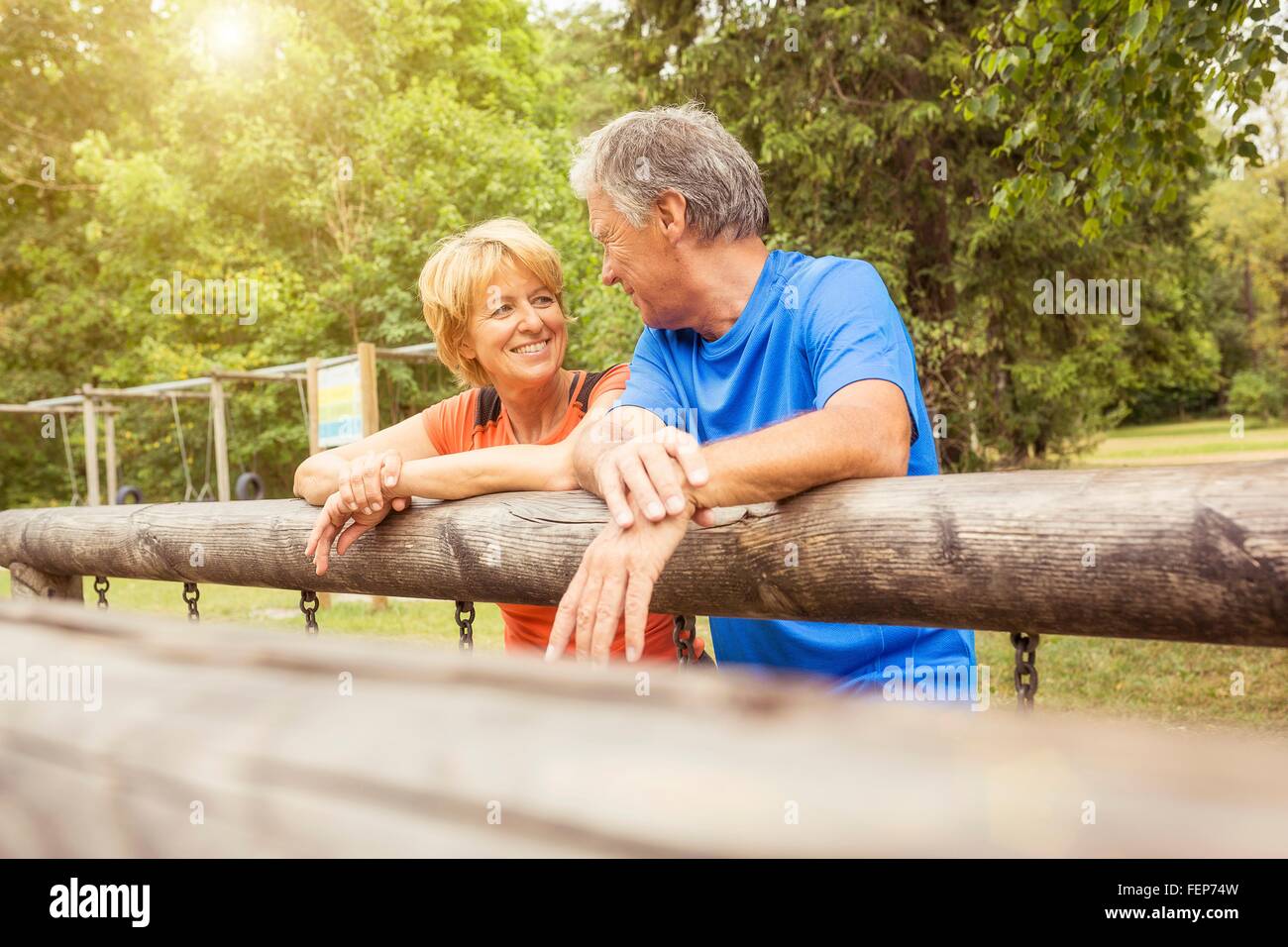 Couple leaning on fence, face to face, smiling Stock Photo
