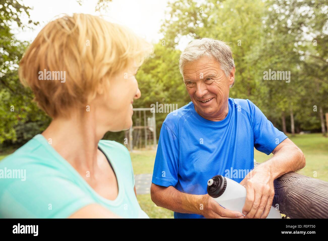 Couple, leaning on fence, holding water bottle Stock Photo