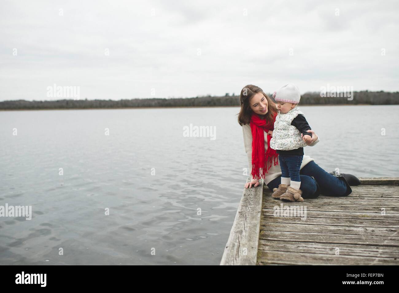 Mother and daughter on jetty, daughter looking at water Stock Photo
