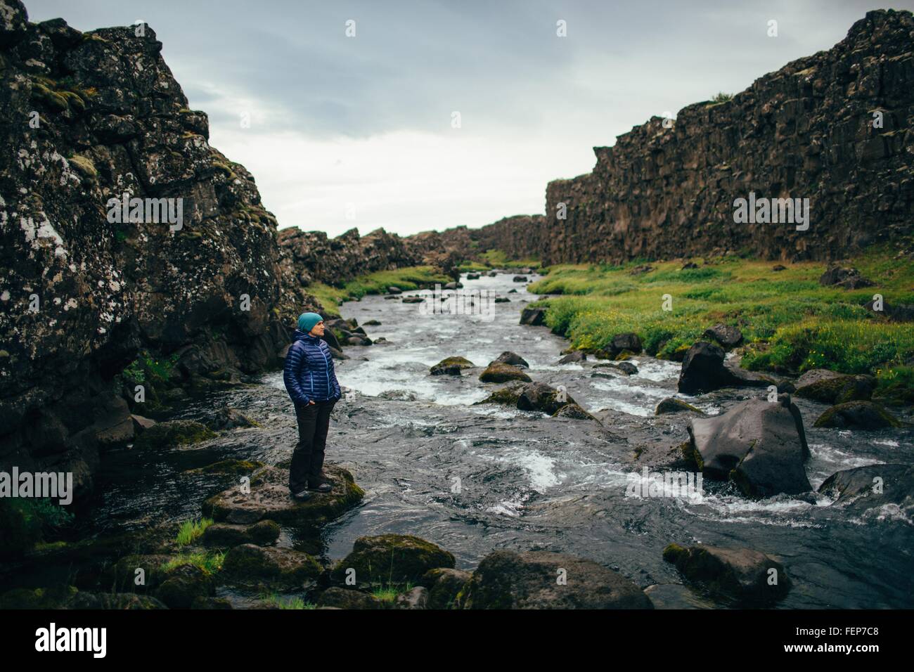 Mid adult woman standing on rock on riverbed, looking away, Iceland Stock Photo