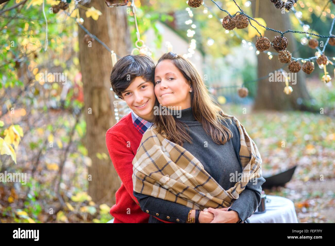 Portrait of teenage son hugging mother in woods Stock Photo