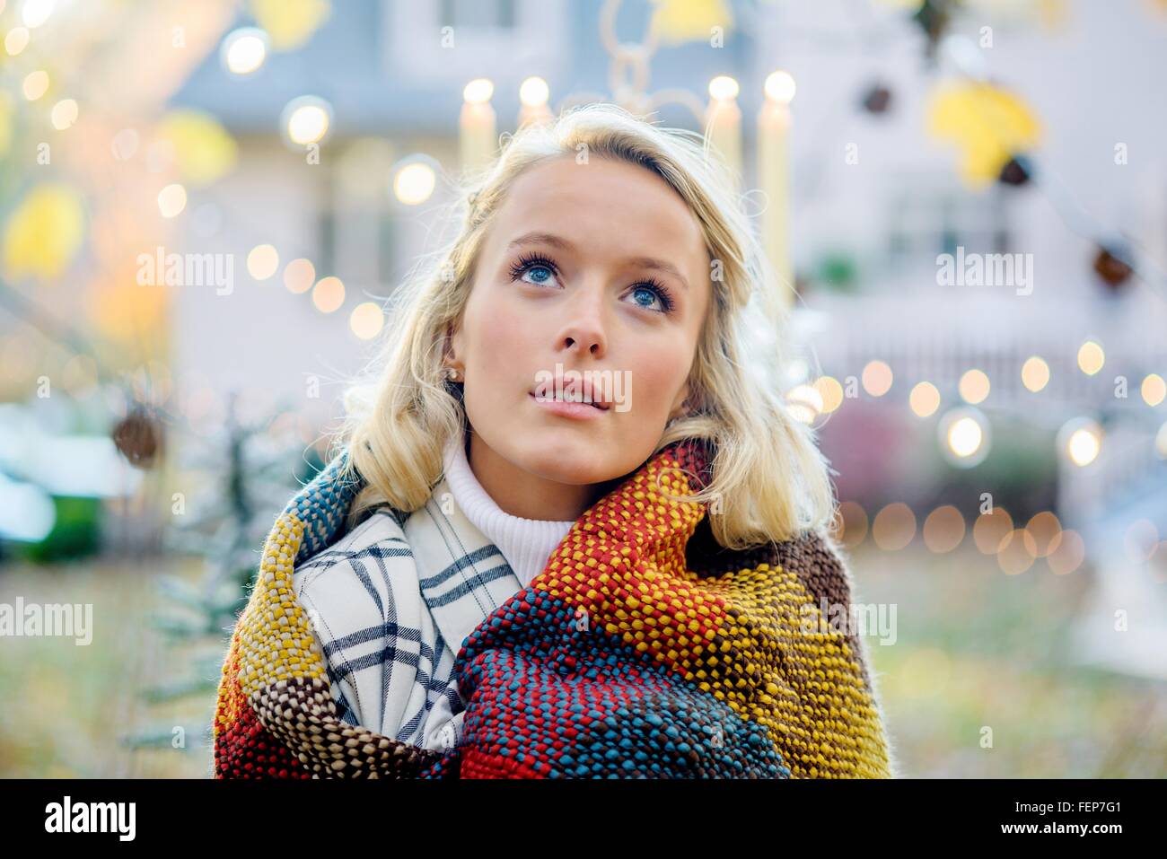 Portrait of young woman wrapped in blanket in front of xmas lights Stock Photo