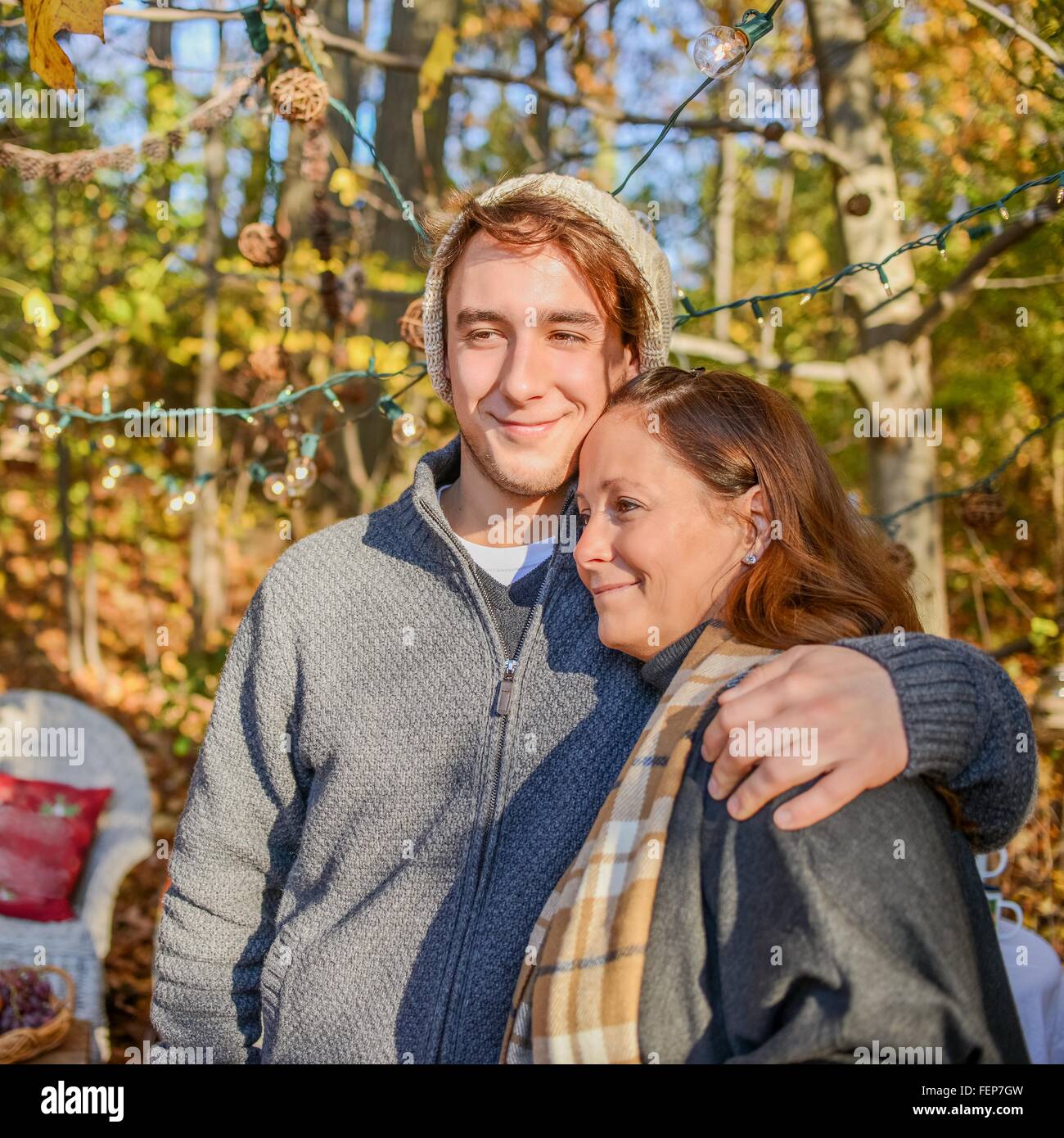 Portrait of young man with arm around mother in woods Stock Photo
