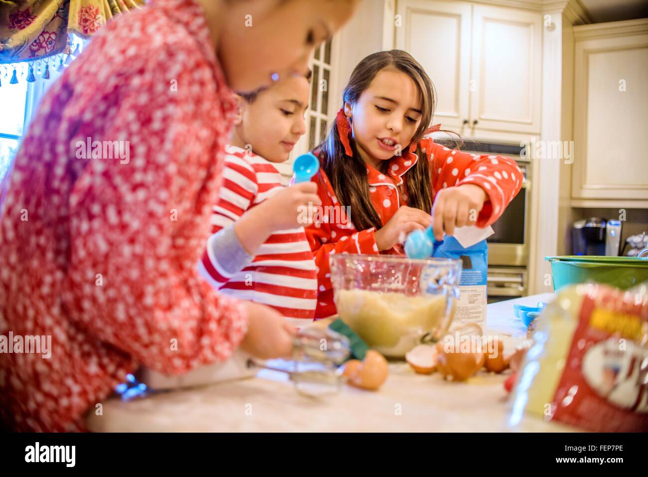 Children in kitchen wearing pyjamas baking Stock Photo