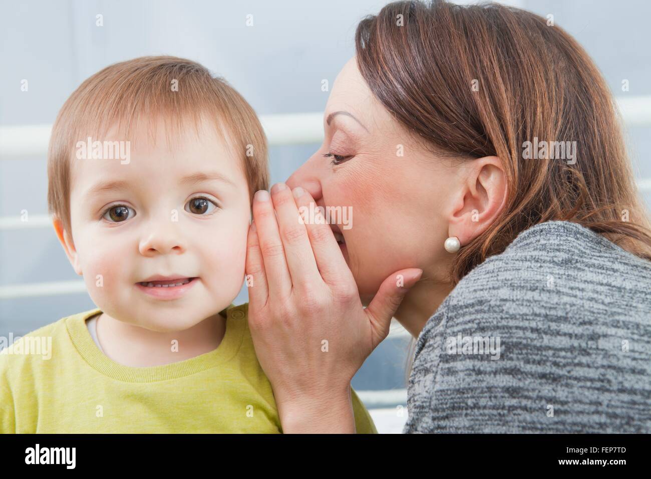 Mother whispering into son's ear Stock Photo