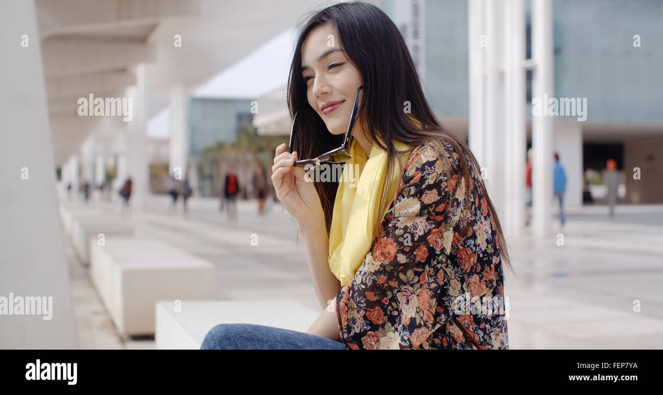 Thoughtful young woman sitting on a promenade Stock Photo - Alamy