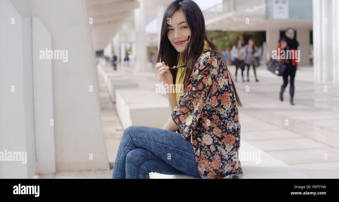 Thoughtful young woman sitting on a promenade Stock Photo - Alamy