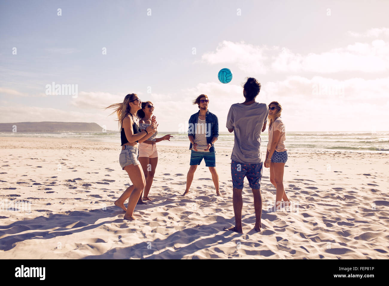 Group of young people playing with ball at the beach. Young friends enjoying summer holidays on a sandy beach. Stock Photo