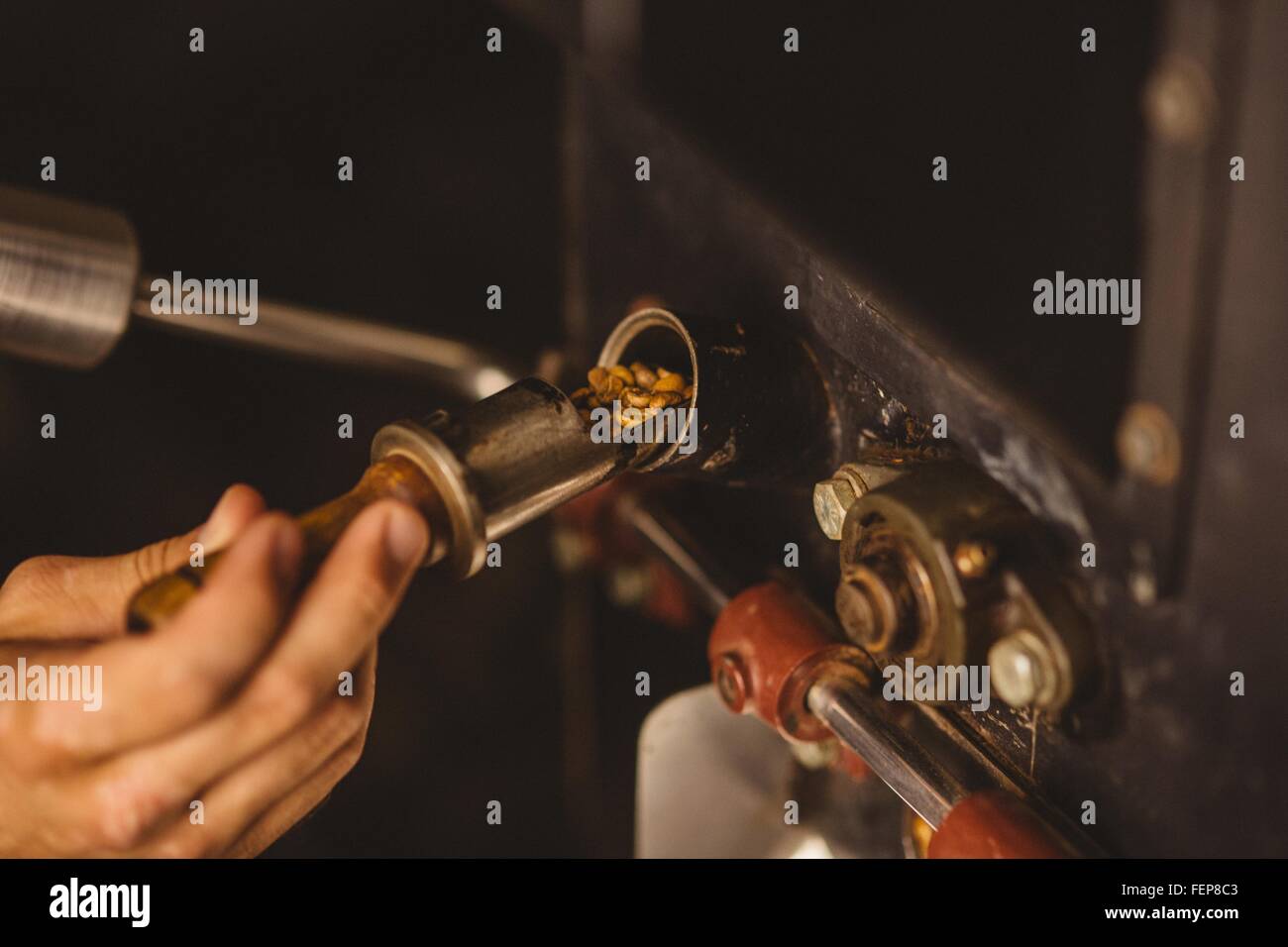 Man pouring coffee beans into coffee roaster, close-up Stock Photo