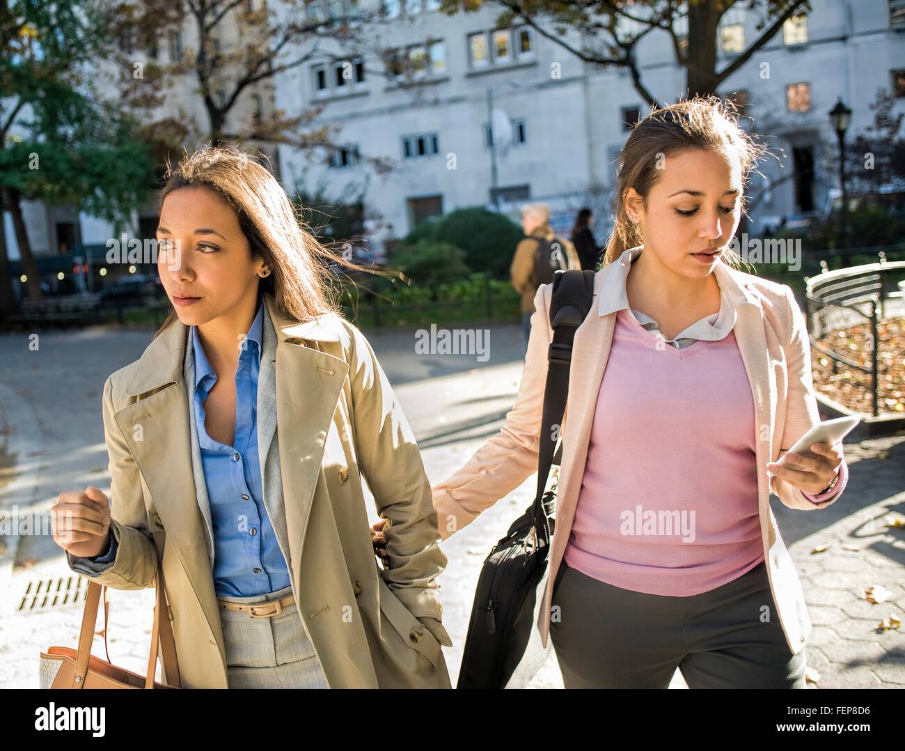 Young adult female twins walking arm in arm through city park Stock ...