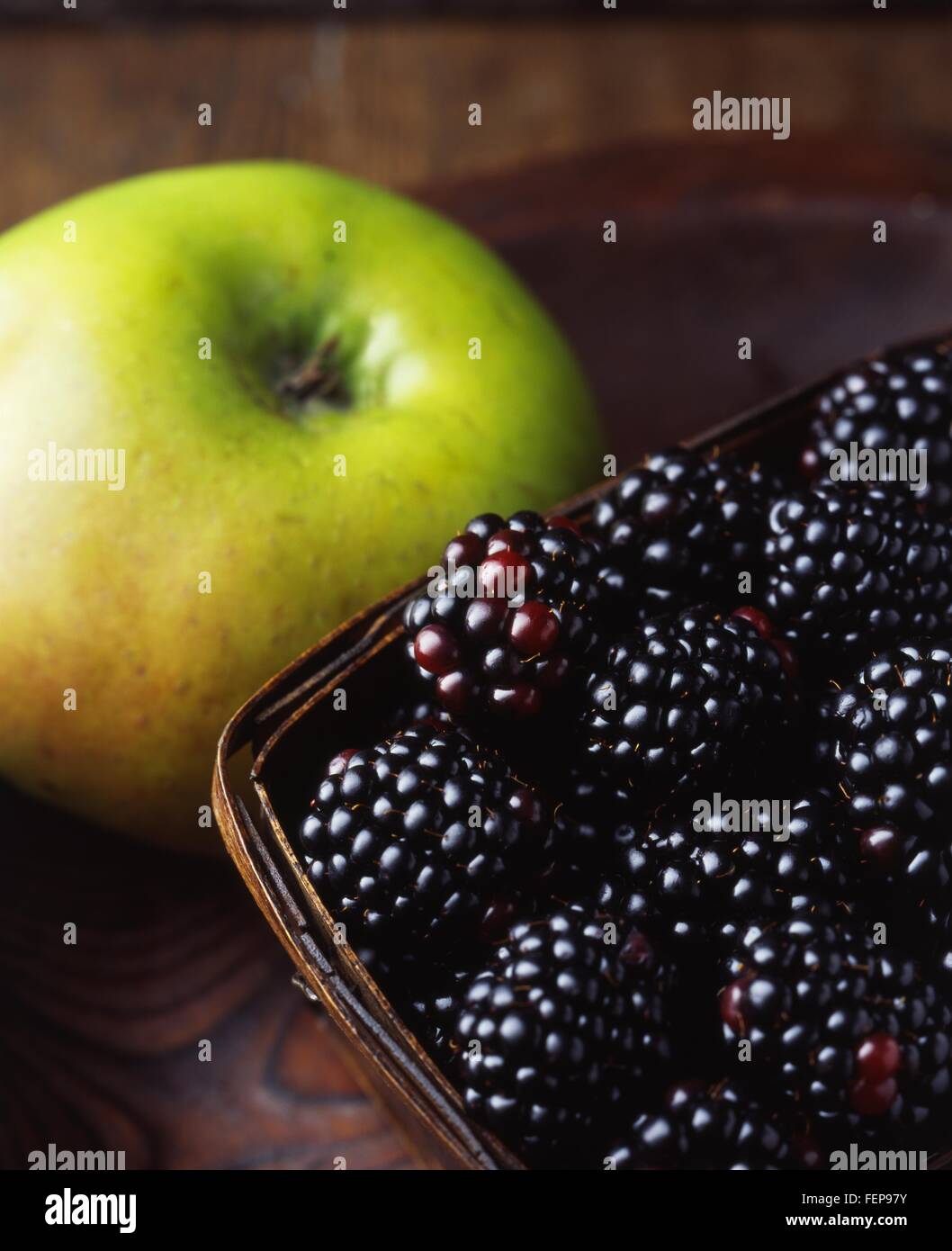 Close up of green apple and blackberries in wooden basket Stock Photo