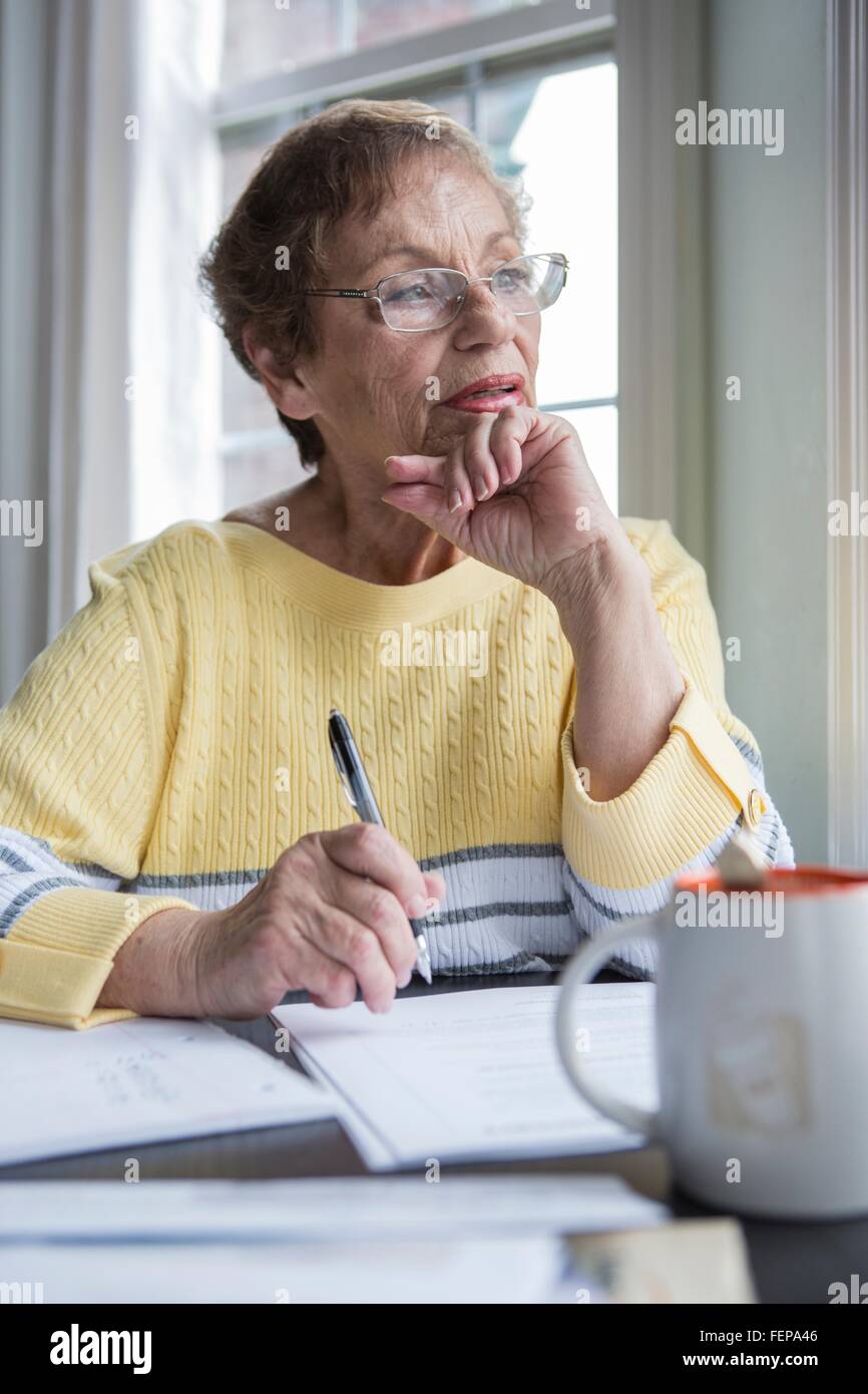 Senior woman thinking at desk Stock Photo