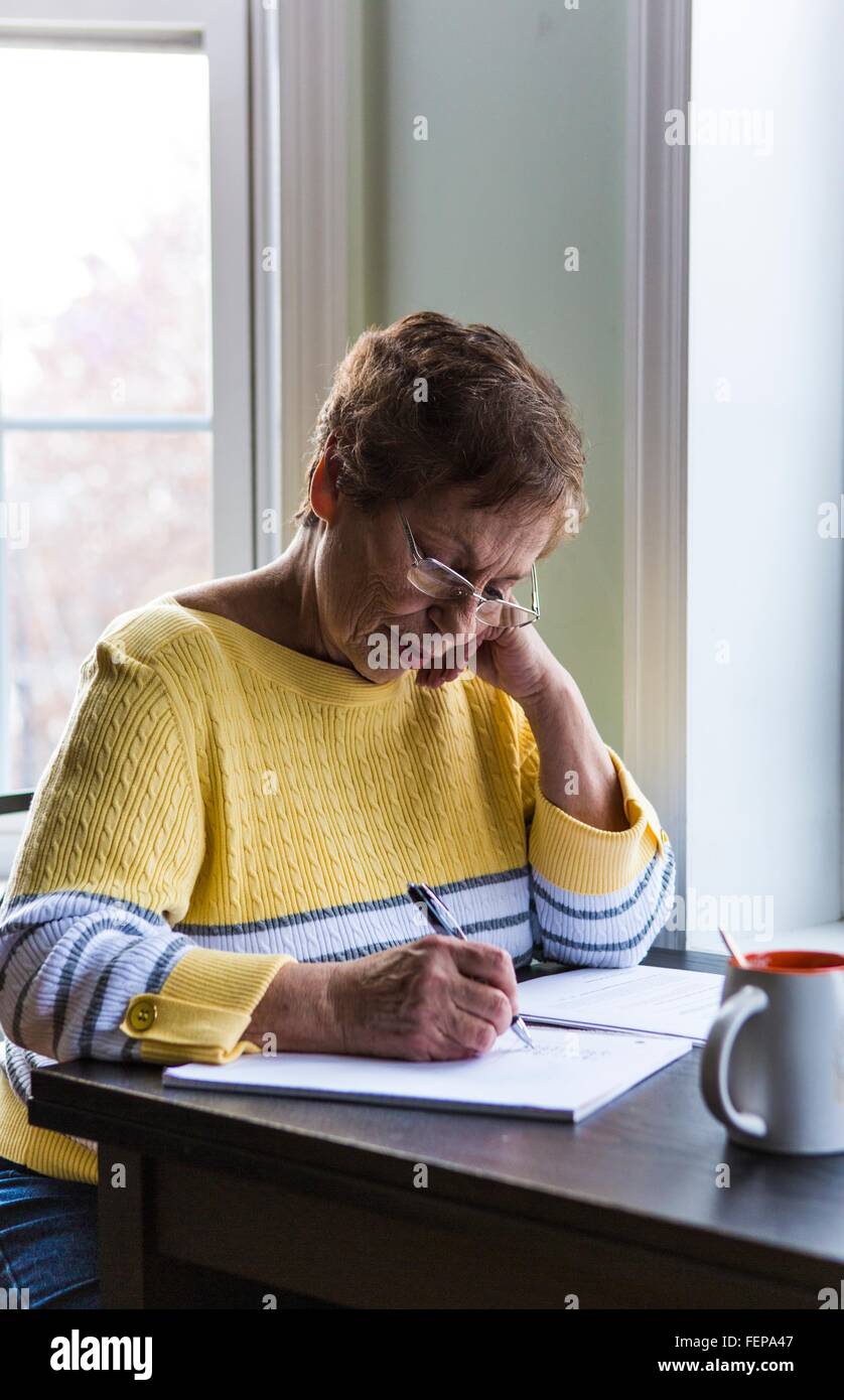 Senior woman writing at desk Stock Photo