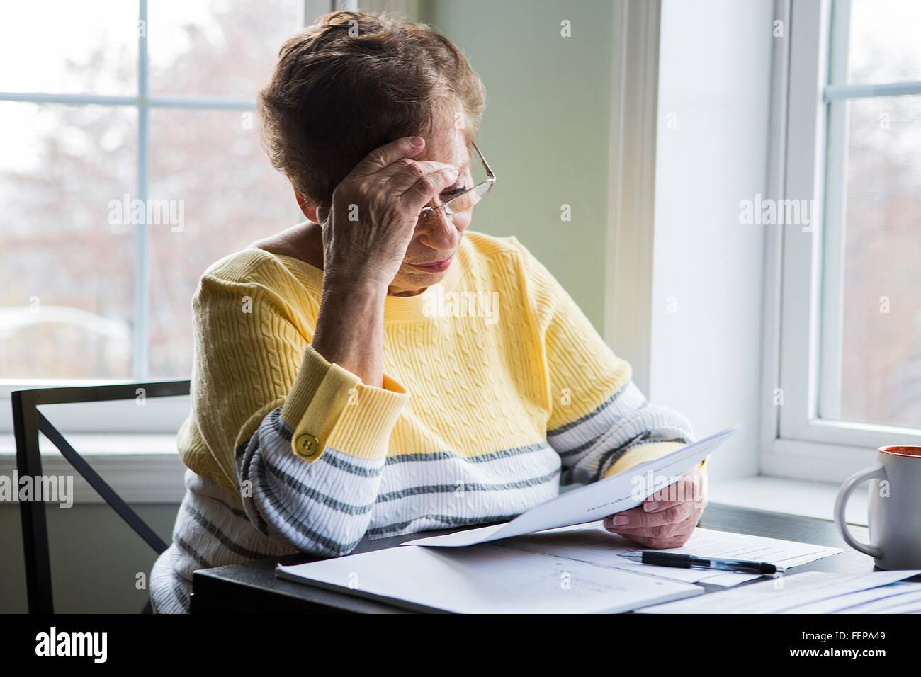 Senior woman reading at desk Stock Photo