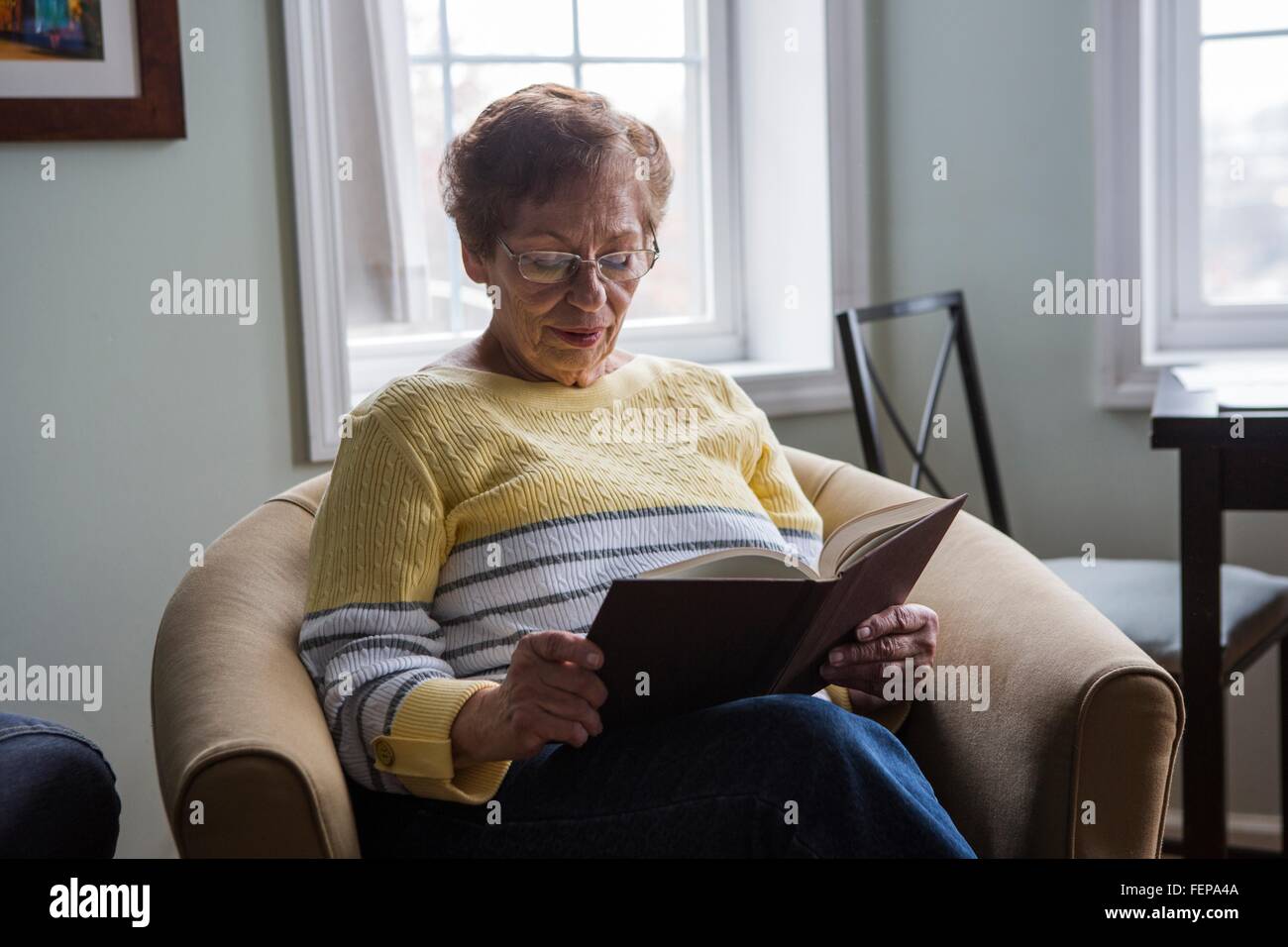Senior woman reading book at home Stock Photo - Alamy