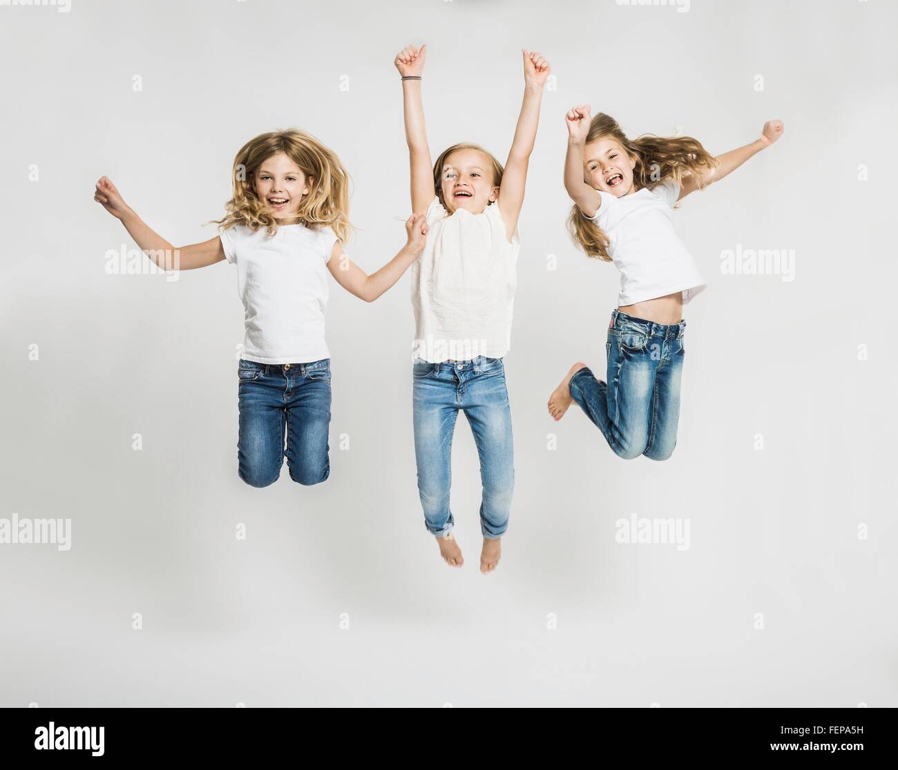 Studio portrait of three girls jumping mid air Stock Photo