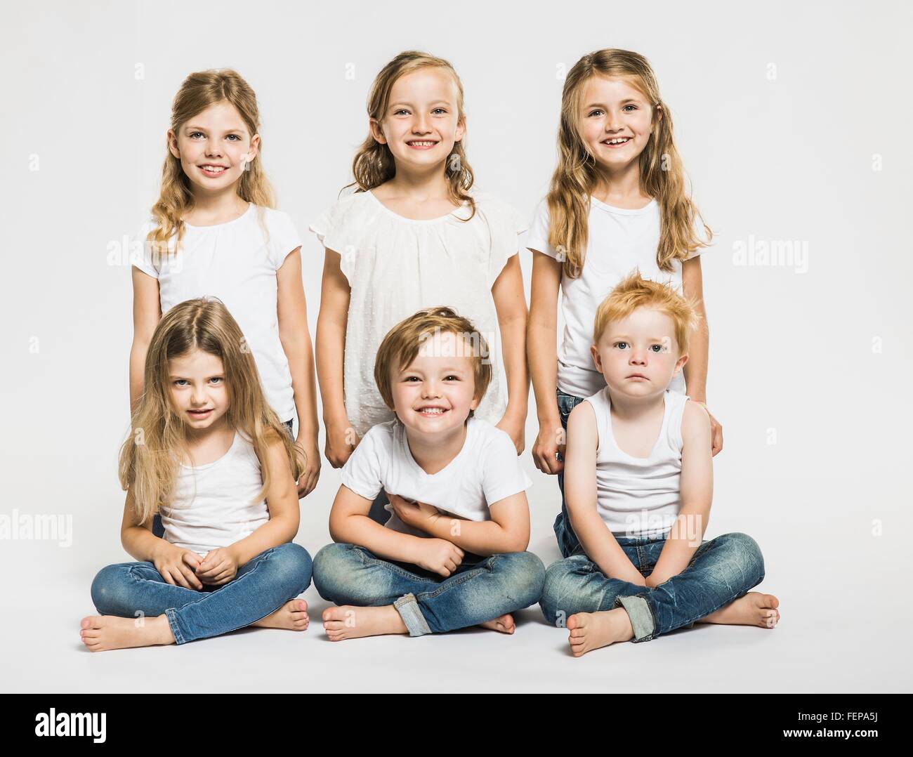 Studio portrait of four girls and two boys sitting cross legged Stock Photo