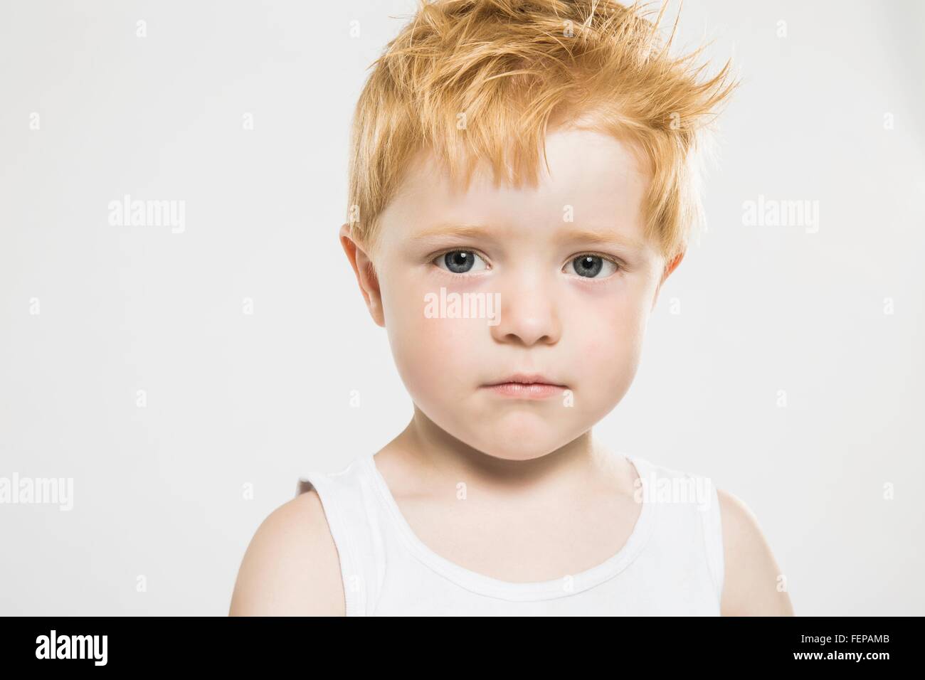 Studio portrait of confident staring boy with ginger hair Stock Photo