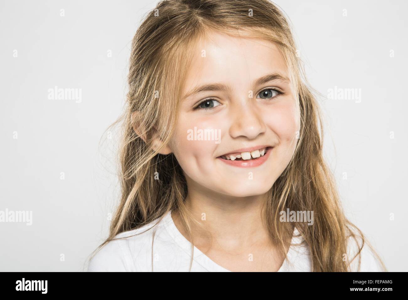 Studio portrait of happy girl with long blond hair Stock Photo
